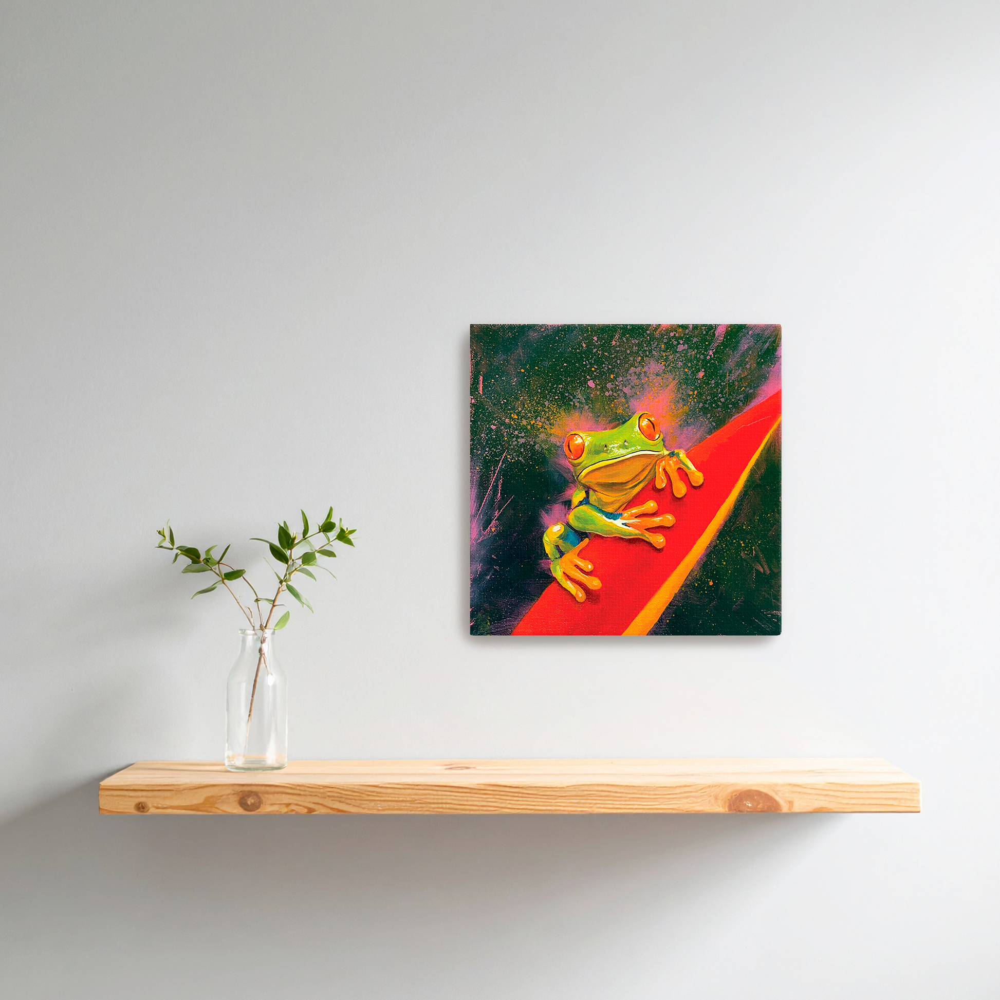 Framed artwork of a colorful tree frog on a red leaf above a wooden shelf with a vase.
