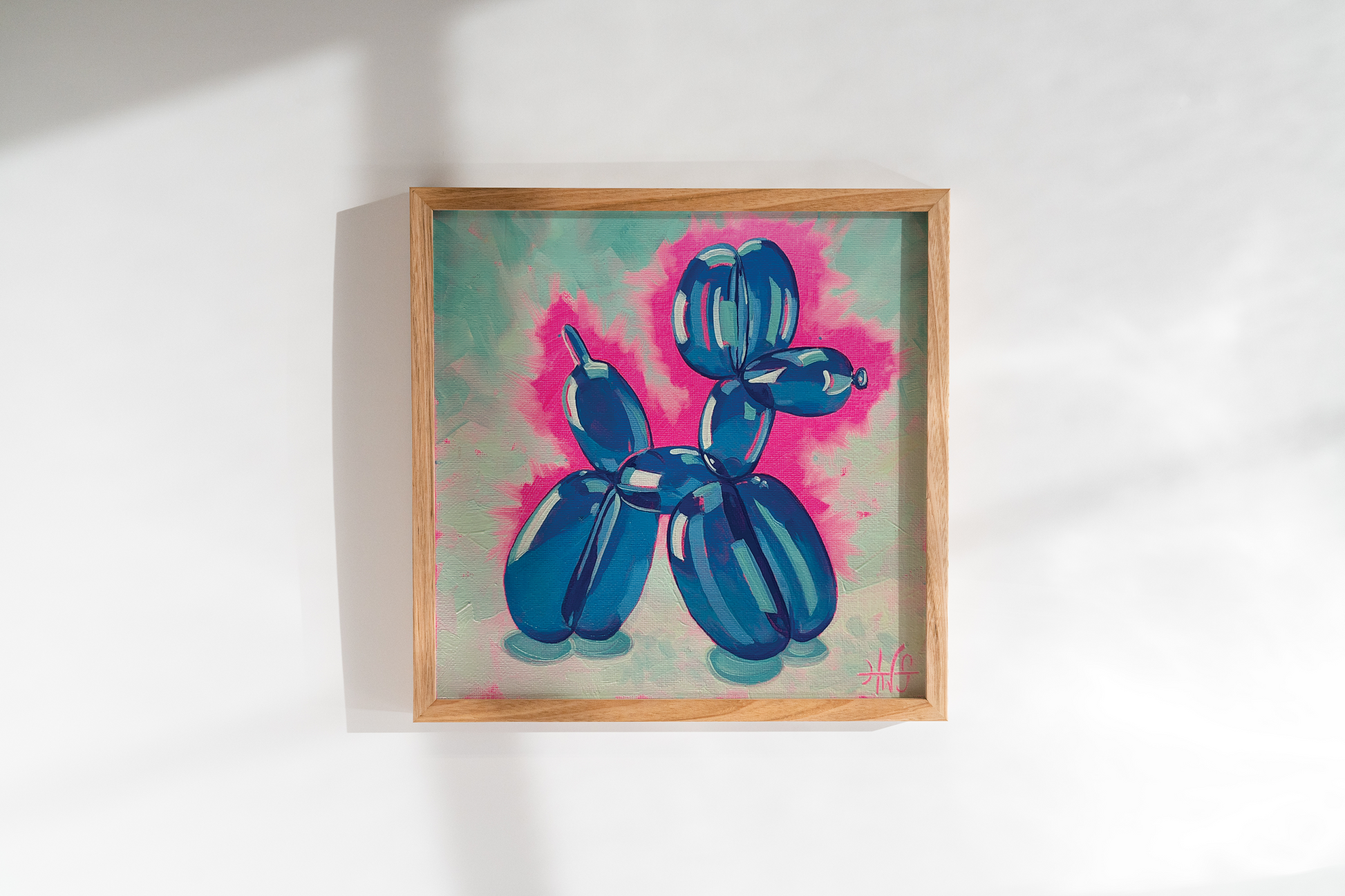Framed artwork of a blue balloon dog on a white wall
