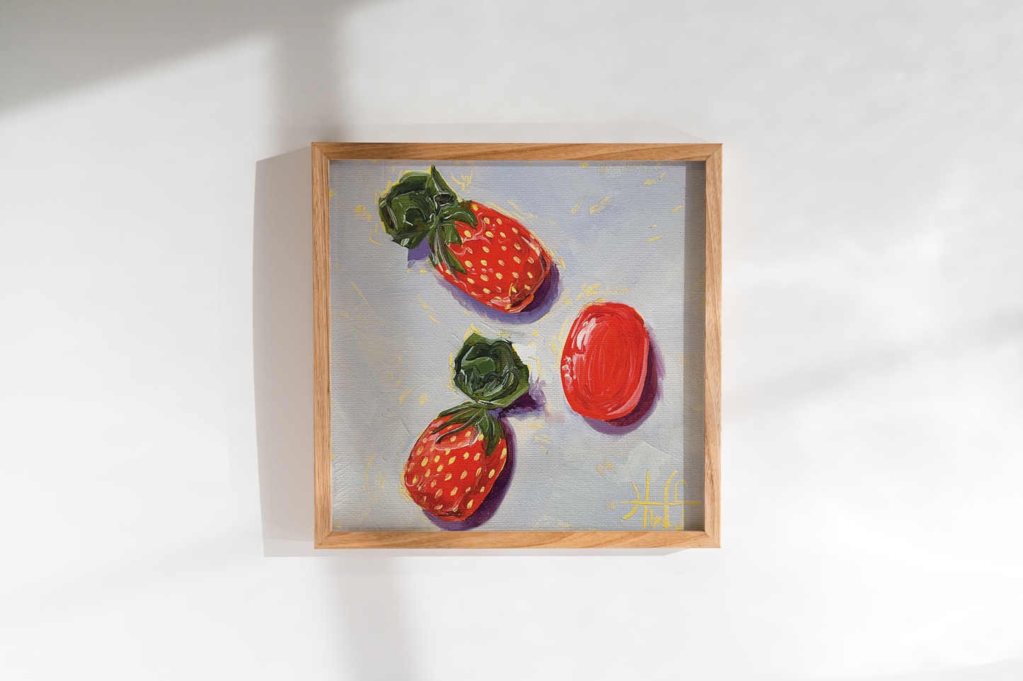 Framed artwork of three red strawberry candies on a white wall