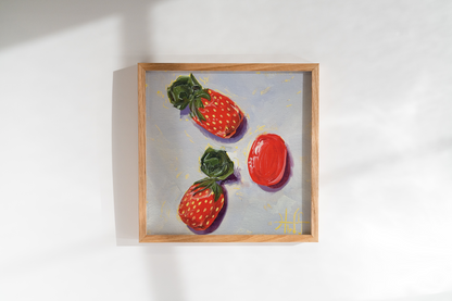 Framed artwork of three red strawberry candies on a white wall