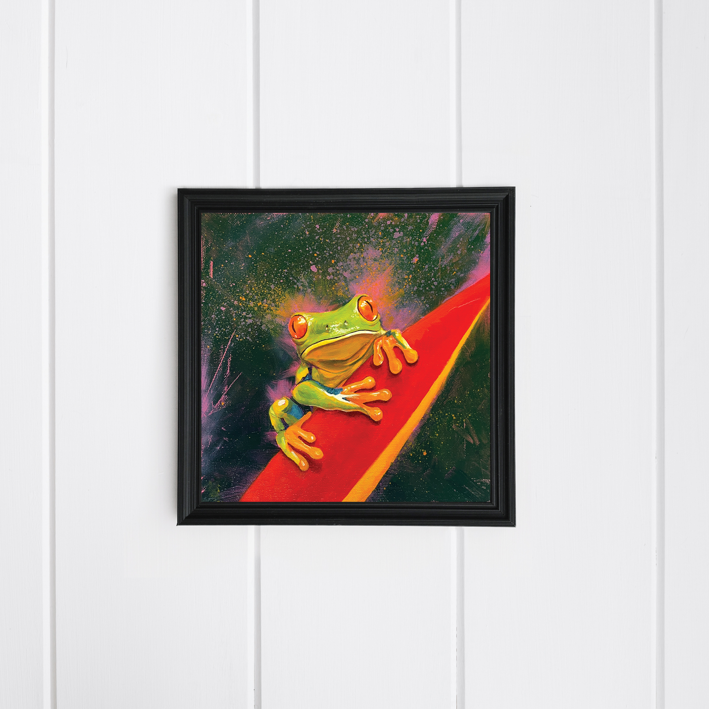 Framed artwork of a green frog on a red leaf 